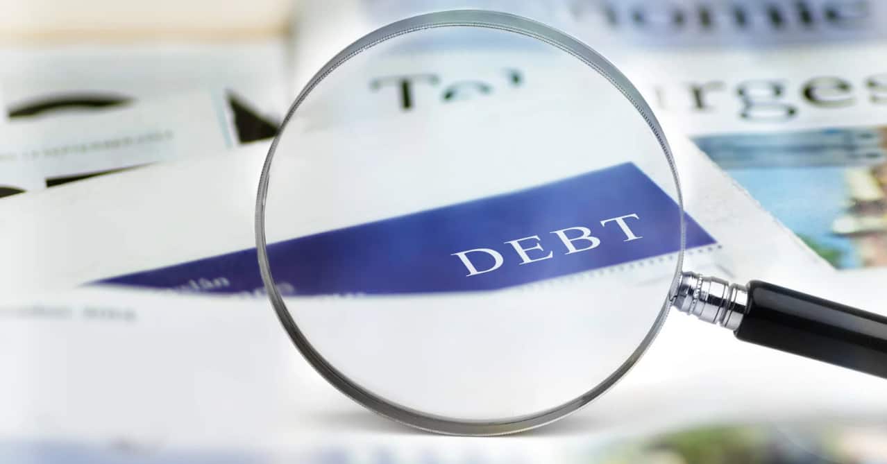 magnifying glass over debt on papers